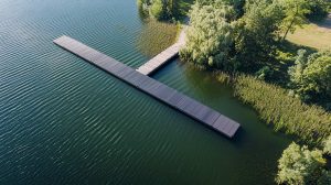 Zu sehen ist ein kleiner Schwimmsteg von Technus, er ist am Rand eines Sees und für Fußgänger zugänglich. Schwimmende Pontons sind angebaut und es ist ein Schwimmsteg